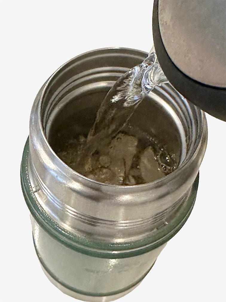 The Stanley food jar in Hammertone green filled with soup ingredients is being filled with hot water to prepare the soup. 正在把裝了湯料食材的Hammertone 綠色Stanley 燜燒壺加入熱水,預備焗湯