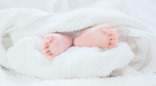 Newborn baby feet wrapped in a soft blanket representing Chinese pregnancy and postpartum confinement traditions 包裹在柔軟毛毯中的新生嬰兒小腳，象徵中式懷孕及坐月傳統