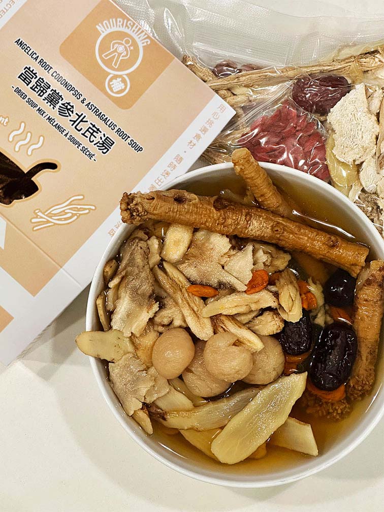 Hong Kong style Angelica Root, Codonopsis and Astragalus Soup with lotus seeds and red dates, shown cooked in a bowl beside vacuum-sealed dried soup ingredients and packaged dried soup mix box by Attitude of Soup Ltd., premium ready-to-cook herbal soup pack made in Canada. 港式當歸黨參北芪補氣湯成品展示，湯碗內有蓮子、紅棗及藥材，旁為真空包裝乾料與湯包盒裝，飲湯思源香港風味養生湯包，加拿大製造即煮湯料。