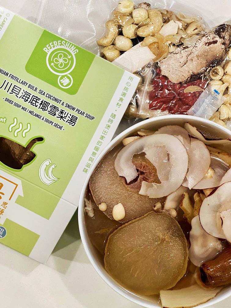 Hong Kong style Fritillary Bulb, Sea Coconut and Snow Pear Soup served in a bowl, shown with vacuum-sealed dried herbal soup ingredients and packaged ready-to-cook nourishing soup mix by Attitude of Soup Ltd., premium Chinese herbal soup pack made in Canada. 港式川貝海底椰雪梨湯成品展示，湯碗內有雪梨、川貝及海底椰，旁為真空包裝乾料與盒裝即煮湯包，飲湯思源香港風味養生湯包，加拿大製造清潤湯料。