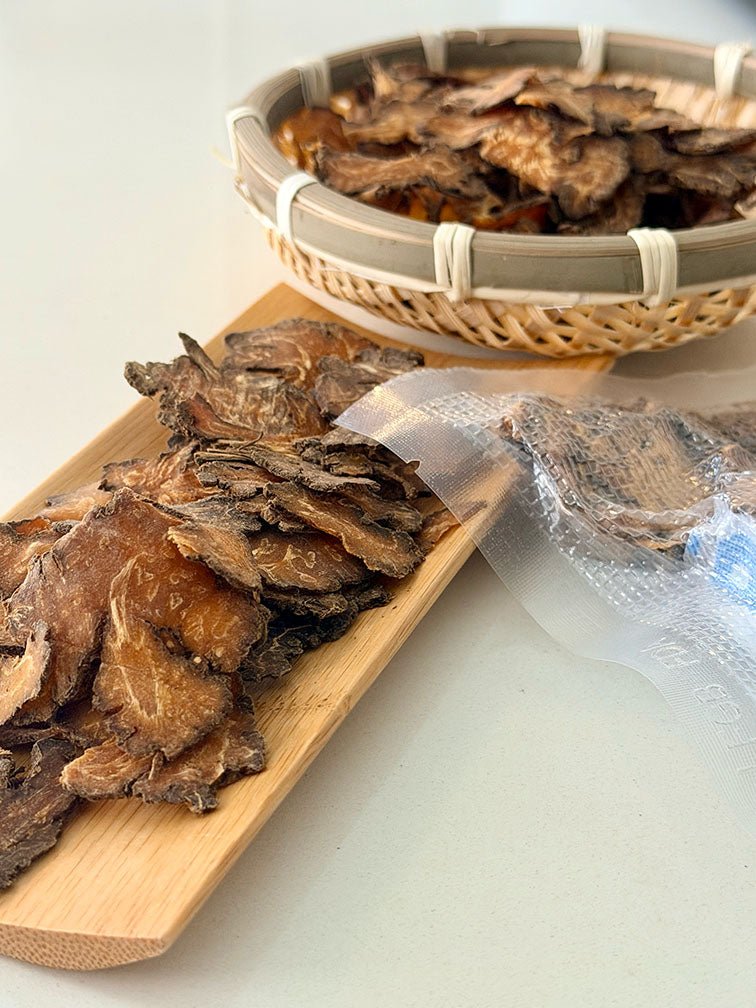 Close-up of dried Chuan Xiong slices with bamboo basket and vacuum-sealed packaging 乾製川芎片特寫，配以竹籃及真空密封包裝展示