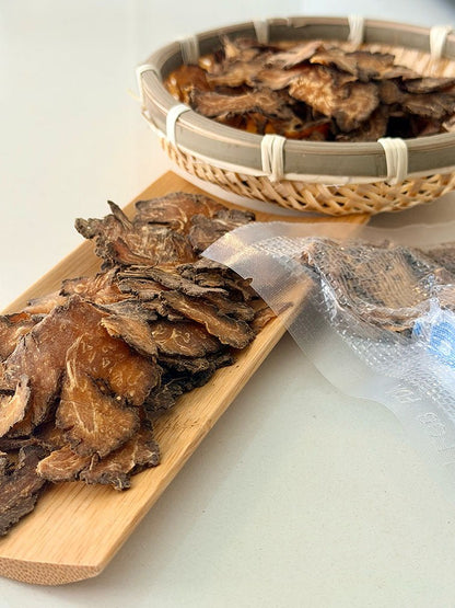 Close-up of dried Chuan Xiong slices with bamboo basket and vacuum-sealed packaging 乾製川芎片特寫，配以竹籃及真空密封包裝展示