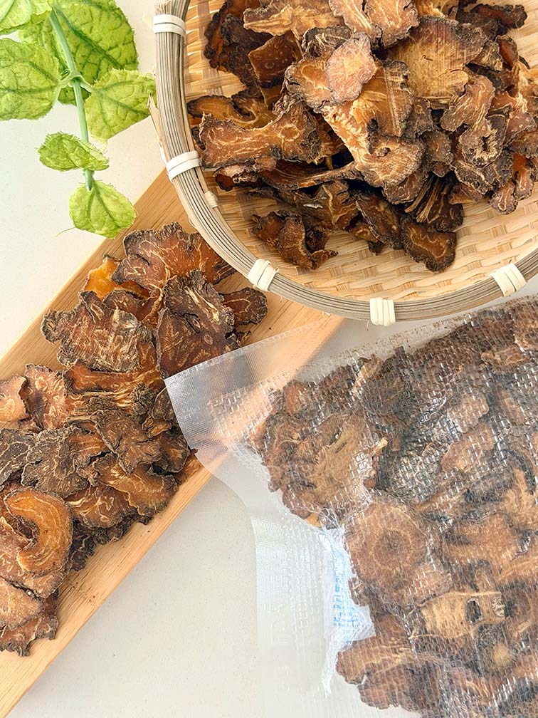 Dried Chuan Xiong Szechuan lovage slices in a bamboo basket beside vacuum-sealed packaging 乾製川芎根莖片置於竹籃中，旁邊展示真空密封包裝