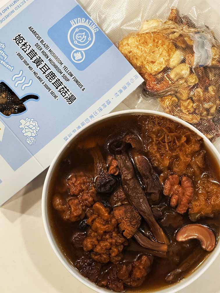Hong Kong style Agaricus Blazei Mushroom, Yellow Fungus and Deer Horn Mushroom Soup served in a bowl, shown with vacuum-sealed dried herbal ingredients and ready-to-cook Chinese soup mix packaging by Attitude of Soup Ltd., premium nourishing soup pack made in Canada. 港式姬松茸黃耳鹿茸菇湯成品展示，湯碗內有姬松茸、黃耳及鹿茸菇，旁為真空包裝乾料與盒裝即煮湯包，飲湯思源香港風味養生湯包，加拿大製造滋養湯料。