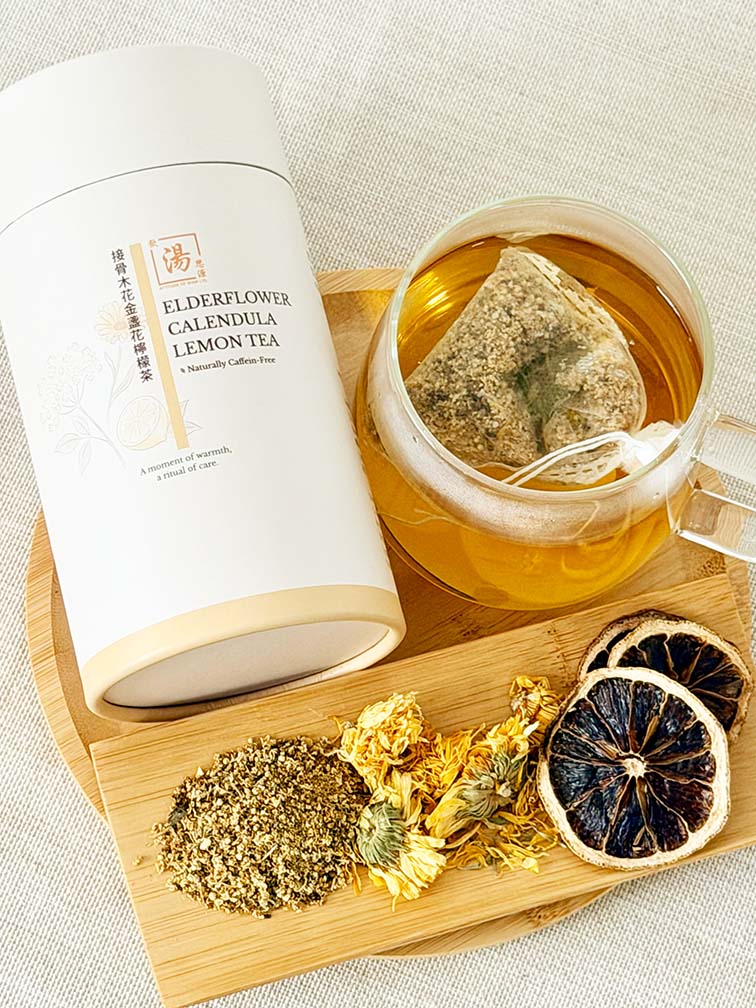 Elderflower Calendula Lemon Flower Tea canister with brewed tea bag and dried elderflower, calendula, and lemon slices on bamboo tray 接骨木花金盞花檸檬茶罐裝、茶包熱泡茶及接骨木花、金盞花、檸檬片擺放於竹盤上