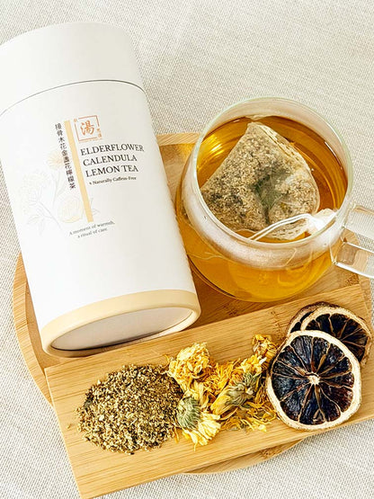 Elderflower Calendula Lemon Flower Tea canister with brewed tea bag and dried elderflower, calendula, and lemon slices on bamboo tray 接骨木花金盞花檸檬茶罐裝、茶包熱泡茶及接骨木花、金盞花、檸檬片擺放於竹盤上