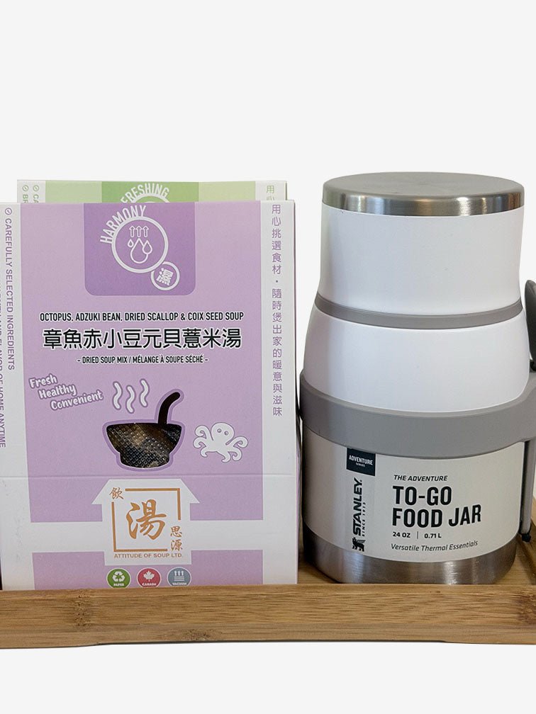 Photo on a wooden tray showing a purple boxed Octopus, Adzuki Bean, Dried Scallop & Coix Seed soup mix next to a white Stanley Adventure To-Go Food Jar with a gray band and stainless-steel lid, against a plain background. 木托盤上的產品照：紫色的章魚赤小豆元貝薏米湯包盒旁放著白色 Stanley Adventure To-Go Food Jar，帶灰色固定帶與不鏽鋼上蓋，背景簡潔。