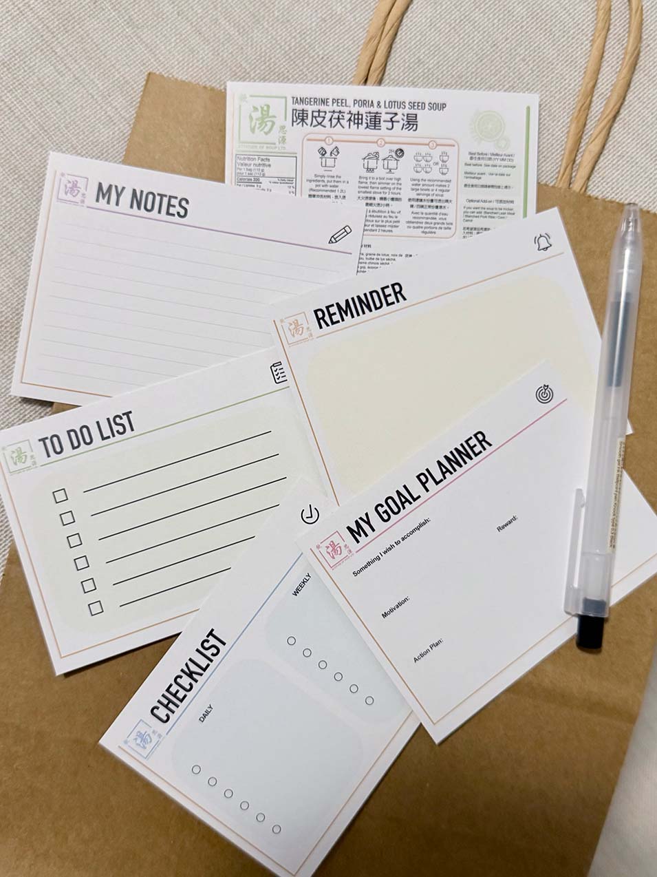 Reusable info cards included with Yum Tong C Yuen minimalist packaging—My Notes, Reminder, To Do List, Checklist, and My Goal Planner—shown with a soup info card and pen on a paper bag. 飲湯思源「極簡約包裝」附送可重用資訊卡背面設計，包括筆記、提醒、待辦清單、Checklist、目標小計劃，配湯包資訊卡與筆，放在紙袋上展示。