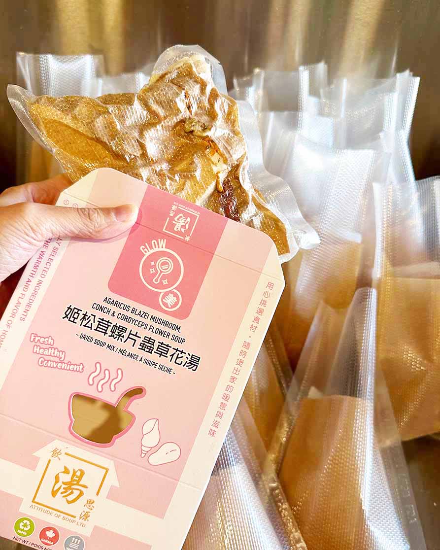 Hand holding vacuum-sealed Hong Kong style dried soup pack with Agaricus Blazei mushroom, conch and cordyceps flower ingredients, premium ready-to-cook herbal soup mix.手持真空密封港式湯包，內含姬松茸、螺片及蟲草花等乾料食材，方便即煮養生湯包。