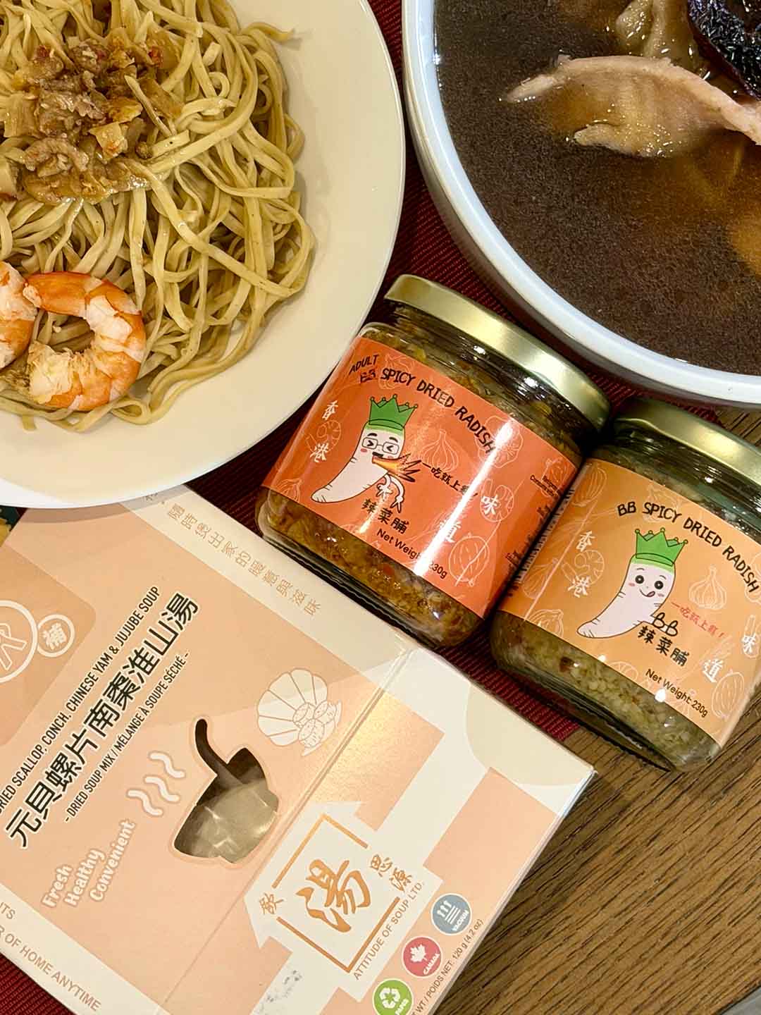 Hong Kong–style home meal with BB spicy dried radish served over noodles, paired with dried scallop, conch, red date and Chinese yam soup, part of a New Year table collaboration set. 港式家常餐桌示意，BB 辣菜脯配麵食，搭配元貝螺片南棗淮山湯，呈現新年餐桌聯乘套裝的家常用餐情境